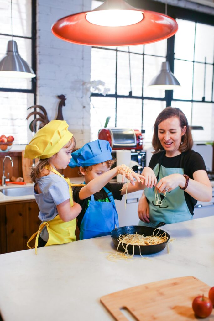 Kids and mom cooking and having fun with pasta in the kitchen
