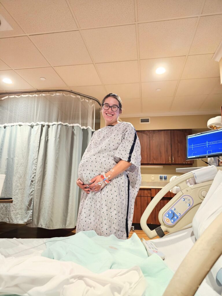 Pregnant woman standing in hospital gown in delivery room