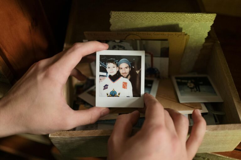 Close-up of hands holding a nostalgic Polaroid photo of father and son from a memory keepsake box.