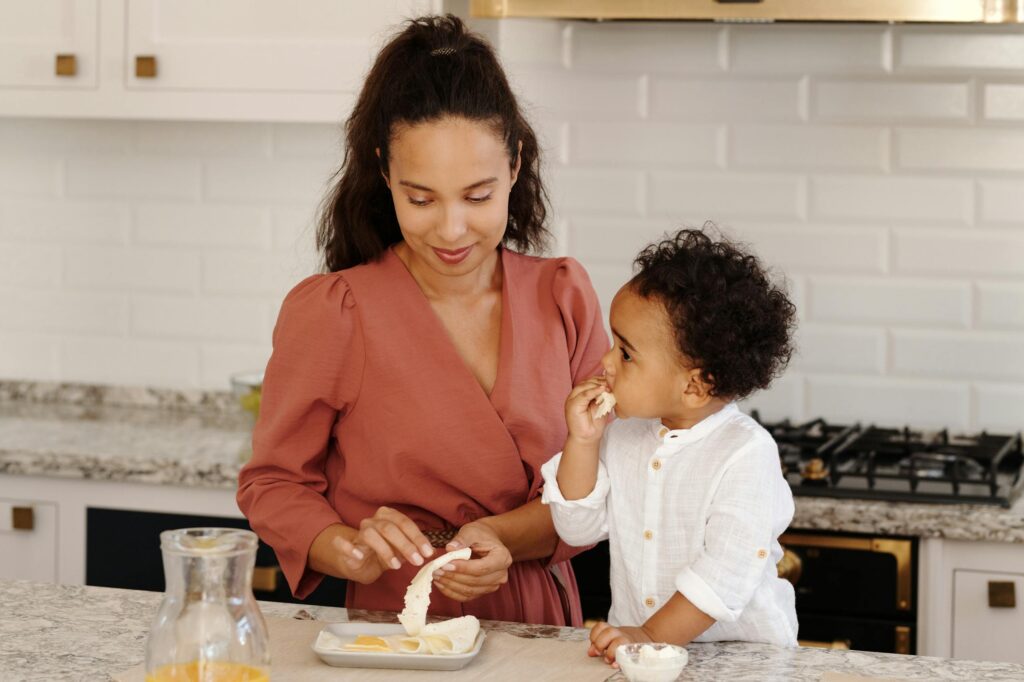 Mom eating and sharing food with toddler Photo by Vanessa Loring Mother and son preparing food together in a modern kitchen setting. Family bonding time.