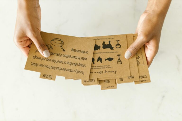 Brown kraft paper recipe cards held by hand on light background to improve your meal planning habits.