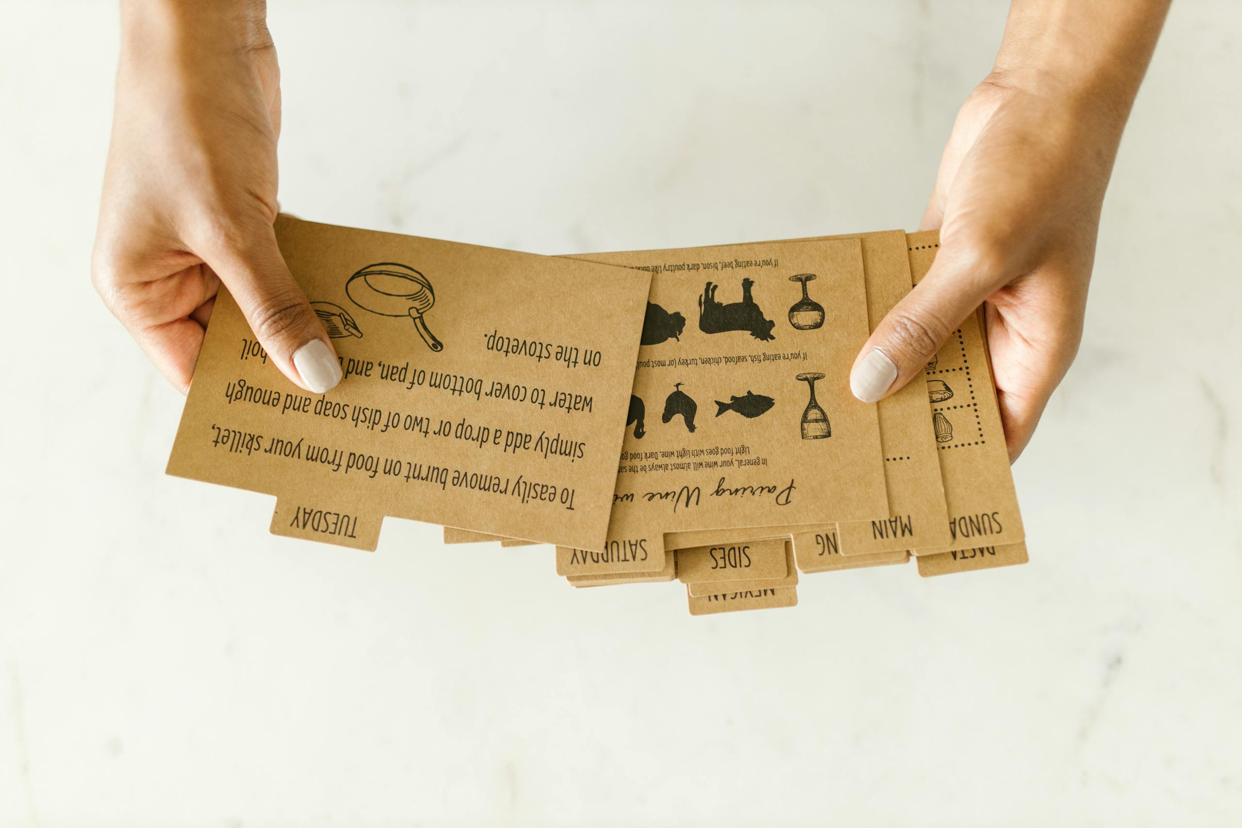 Brown kraft paper recipe cards held by hand on light background to improve your meal planning habits.