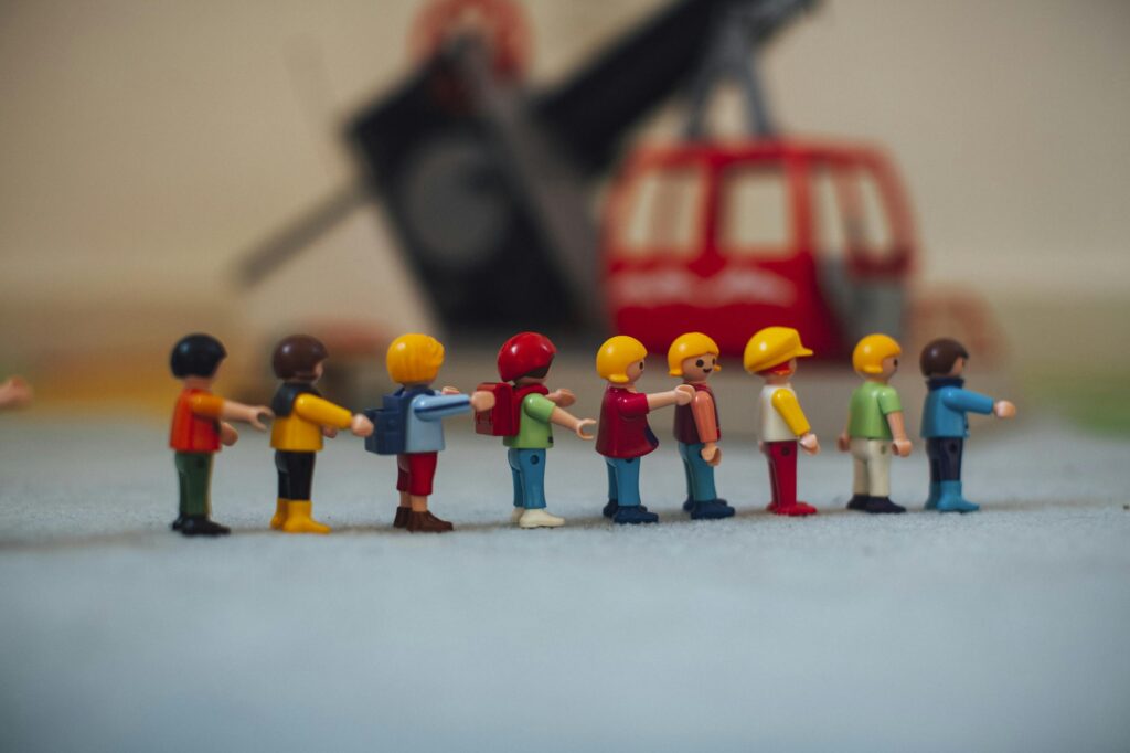 Miniature plastic figures lined up in front of a toy helicopter, which can be kept in a toddler diaper bag.